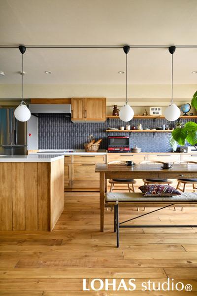 台形を敷き詰めたような壁面のタイルがお洒落なキッチンです。壁面の収納カウンターはウッドワン製ですが、特注でLOHASオイル塗装とすることにより、他の家具や床と色味を合わせることに成功しています。