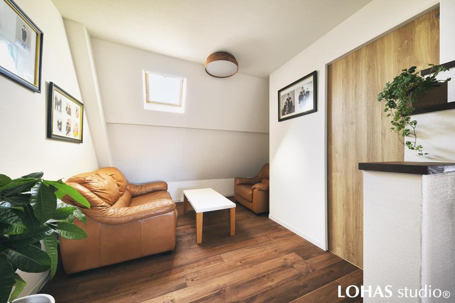 家族の写真が飾られ、思い出のぎゅっと詰まったファミリーホールです。壁に額を飾ることで、自然とリズムが生まれいきいきとした印象に。デッドスペースになりがちな勾配天井をうまく活かしたつくりとなっています。