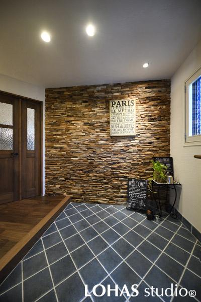 ランダムに貼られたチークの古材が味わい深いエントランスです。スペースを広くとり、ゲストが来てもラクラク。正方形のタイルを四半目地貼りすることでアクセントを付けました。