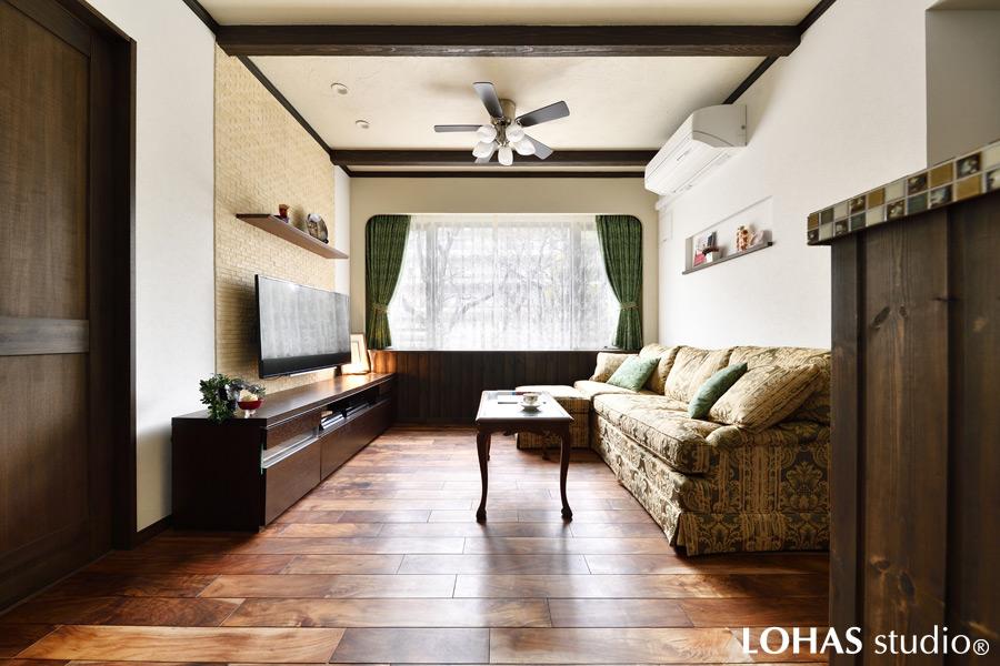 アンティークな雰囲気の漂う上品なLDKです。天井の疑似梁とリビングの羽目板、キッチンカウンターや巾木といった、各所にちりばめられたダークブラウンが空間を引き締め、より格調高い印象を強めています。