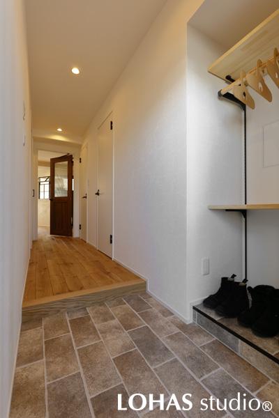 玄関扉のすぐ脇にはオープンのシューズクロークが。可動棚で自在に高さを調節でき、コート掛けも備えているのでとても便利です。レトロな石畳を思わせるフロアタイルと木目調で、暖かみのある玄関となりました。