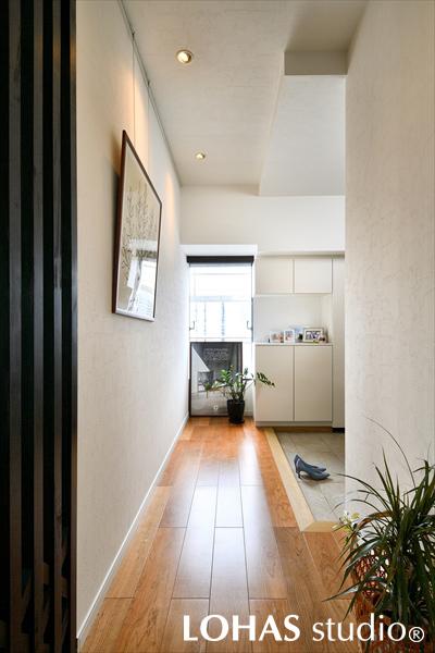 土間から直接靴で上がることのできる大容量のウォークスルークローゼットを設けた玄関です。そのままリビングに抜けることもできて非常に便利。リビングとの間仕切りにはデザイン格子を施工しています。キッチンの斜めタイルとデザインをリンクさせることで、全体の統一感がアップしました。