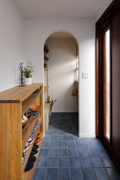 シンボルカラーのブルーをタイル施工した玄関です。2世帯家族に必要となる大きな収納スペースをシューズクローク・収納家具で確保。