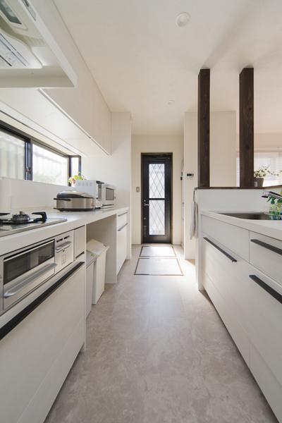 白基調でまとめた対面キッチンです。シンク側(右手)はアイランド仕立てで回遊OK。勝手口(奥)付近にはパントリーを設えました。