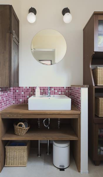 ピンク色のタイルバリエーションや丸鏡で可愛らしい雰囲気の洗面室です。吊り戸や洗面棚を造作して収納力がアップ！