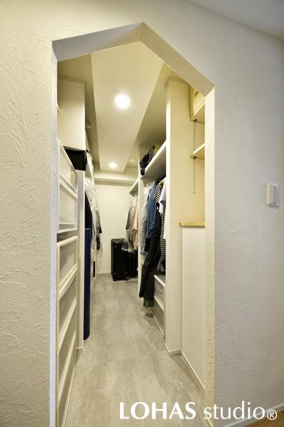 廊下に面したウォークインクロゼットは、なによりも三角屋根の形をした下がり壁に目を奪われます。中は大容量の収納スペース！家族全員の衣類が収まるように衣類ハンガー用のパイプを長く渡し、鞄などが仕舞えるよう枕棚も造作しています。