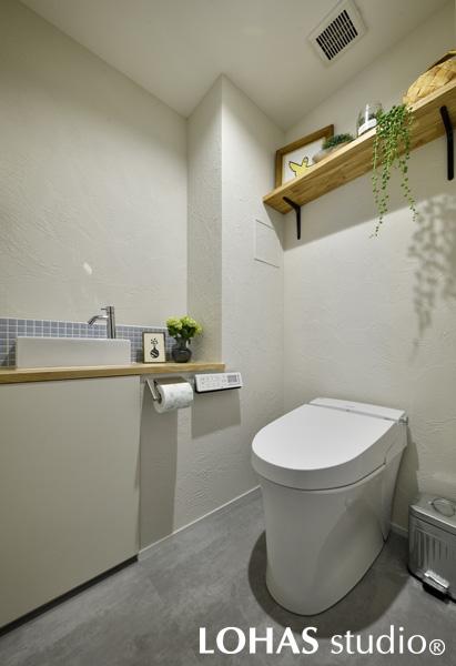 シンプルにまとめたトイレです。パウダールームと同じタイル・フロアタイルを用いて、水まわりに統一感を出しました。壁には珪藻土を用いてにおいの対策もばっちり。天井は珪藻土柄のクロスにしてコストダウンを図っています。