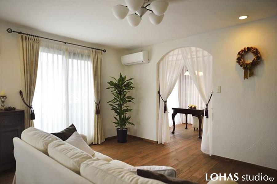 アトリエへの出入口をカーテンで間仕切りしたリビングです。珪藻土で壁を彩り優美なフレンチテイストに仕上げました。床は芳醇なブラウンカラーです。