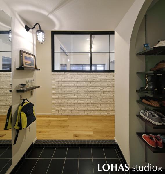 室内窓で明るくなった開放的な玄関です。照明には個性的なマリンランプをご採用。壁のブリックタイルが上質な雰囲気です。右手のシューズクロークは便利な可動棚タイプ。