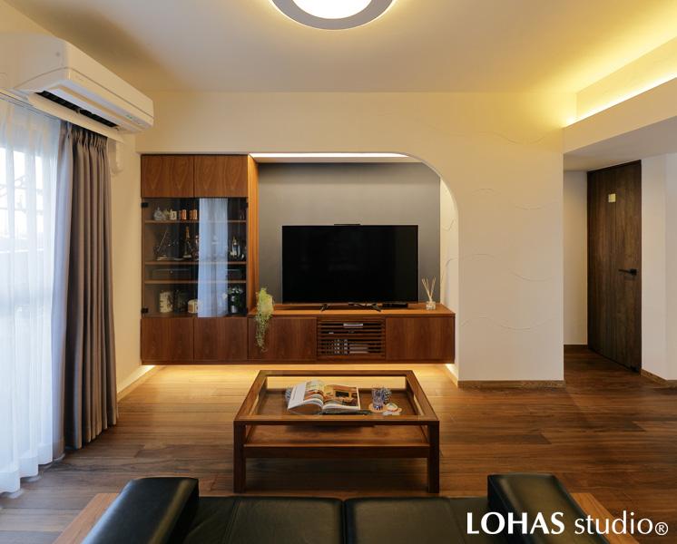 ウォールナットの突板で高級感のあふれるシックなリビングです。木目の美しいTVボードは、LOHAS studio大宮店の家具も手掛けた「KOMA」にオーダーしたもの。背面には、ご主人こだわりのブラッシュスウェードと呼ばれる陰影の出る塗装を施しました。上下に取り付けた間接照明の光で陰影がより引き立つよう