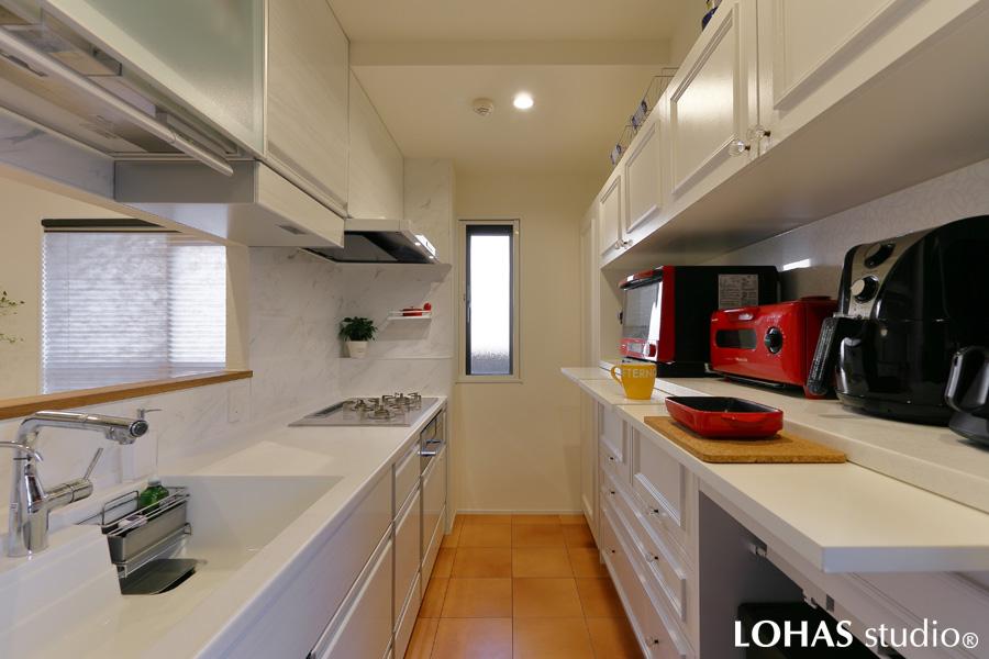 清潔感たっぷりなホワイトで統一されたキッチンです。小上がりスペースと対面式になっているため、配膳もスマート。後ろにはモールディングが美しい収納を取り付けました。一見普通のように見えて、奥様の為だけに作られた、機能が盛りだくさんのオートクチュール収納。「家族分の配膳が一度にでき、毎日のお弁当作りにも大