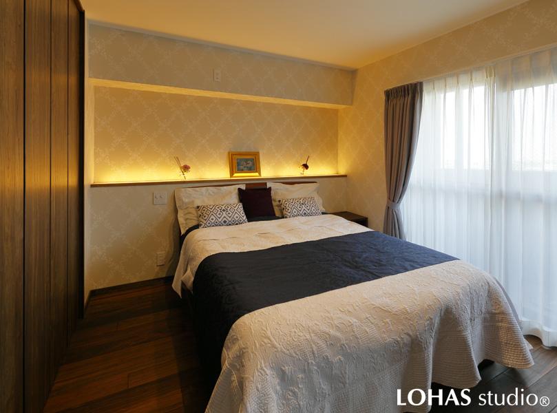 控えめなボタニカル柄のデザインクロスを採用して、ホテルのような佇まいとなったご夫婦の寝室です。壁をくり抜いたような巨大なニッチには、ここにも間接照明をご採用。ふわりと浮きあがるような下からの光が雰囲気のある空間となりました。