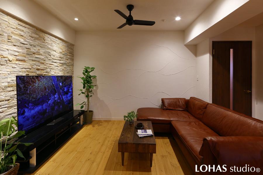 天然石製のアクセントウォールで上質な一角となったリビングです。こちらも高い天井を活かし、ダウンライトでシアタールームのような雰囲気に。快適に過ごせるようにと、側面は珪藻土を用いています。スタジオで見たHさまが気に入られて採用となった塗りパターンは、光によって陰影が生まれるウェーブパターンです。