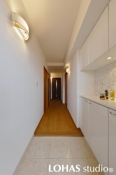 ホワイト中心の上品な玄関です。玄関収納は既存のものをそのまま活用し、壁にモザイクタイルをあしらいました。天然の貝で作られたモザイクタイルは、Hさまがショールームで選び抜かれたお気に入りのもの。パールのような輝きが、ダウンライトでさらに際立ちます。