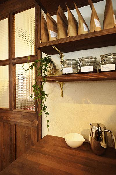 コーヒーサーバーやドリッパーなど、細々とした商品を置けるよう作られた棚は、同社オリジナルの玄関収納棚を上手に活用してデザイン。写真左の風合い豊かな引き戸も、同社のオリジナル。無垢材を使用した自然素材の引き戸、収納棚と真鍮製の金物が、どこか懐かしさを感じさせ親近感が湧く。