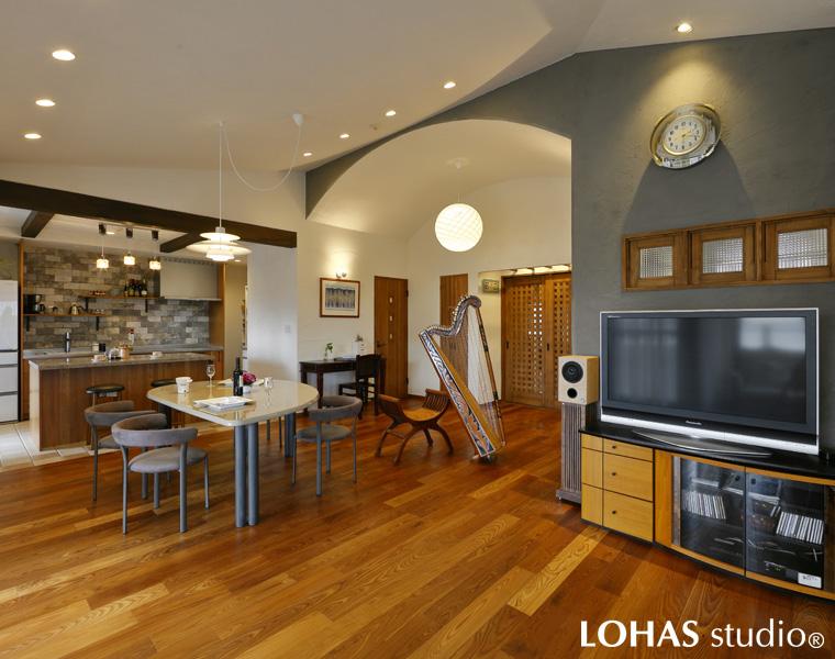 優美なアーチ型の天井が印象的なLDKです。ご夫婦のお話をヒアリングしてデザイナーが真っ先に思いついたのが、奥さまのご要望であるアルパの演奏会スペースでした。高い勾配天井をそのまま活かし開放感のあるつくりにしているため、演奏会でたくさんのゲストを迎えても窮屈な印象になりません。