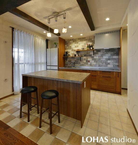 回遊性があり使い勝手のよいキッチンです。イギリスの田舎の雰囲気がお好みなご主人さまのために、化粧梁や風合いのある古レンガを模したタイルなどをセレクト。木製のキッチンを設置して、モダンながらも温かみのある空間となりました。