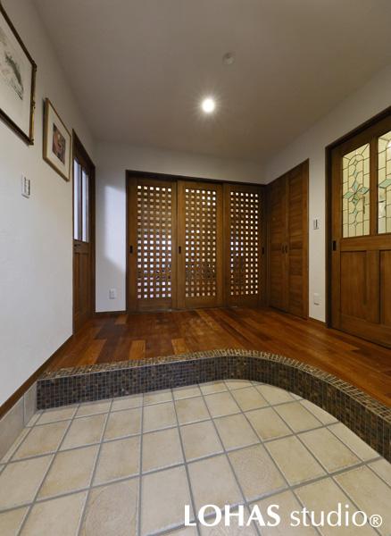 広々とした玄関の様子です。3枚の引き戸を格子にし、ガラス越しにLDKが覗くようにしたことで、ホール特有の圧迫感をなくしました。建具はフローリングに色を合わせ、格調高い印象をより強めています。