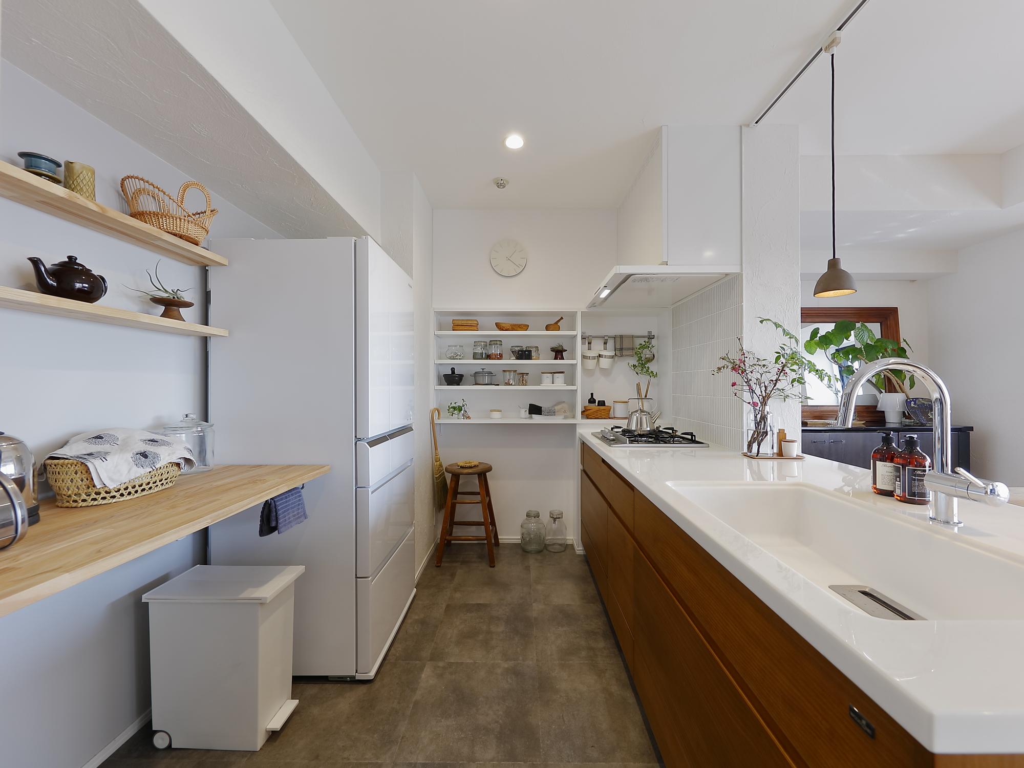 ナチュラルな印象の強いキッチンまわりです。老朽化していたキッチンは無垢材の扉が特長のウッドワン製をご採用いただきました。広くとった空間を楽しんで活用いただけるように、よく使う道具置き場メインの棚と飾りメインの棚と、それぞれ素材を変えて造作しています。