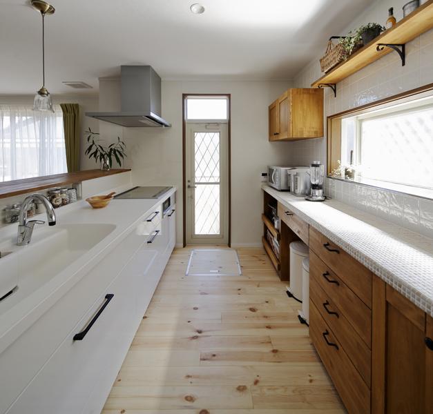 カントリー風の清楚なキッチンです。白い建具やタイルが光を反射して明るい室内。カップボードやカウンターはオリジナル造作品。耐震補強を施して快適な家事動線も実現！