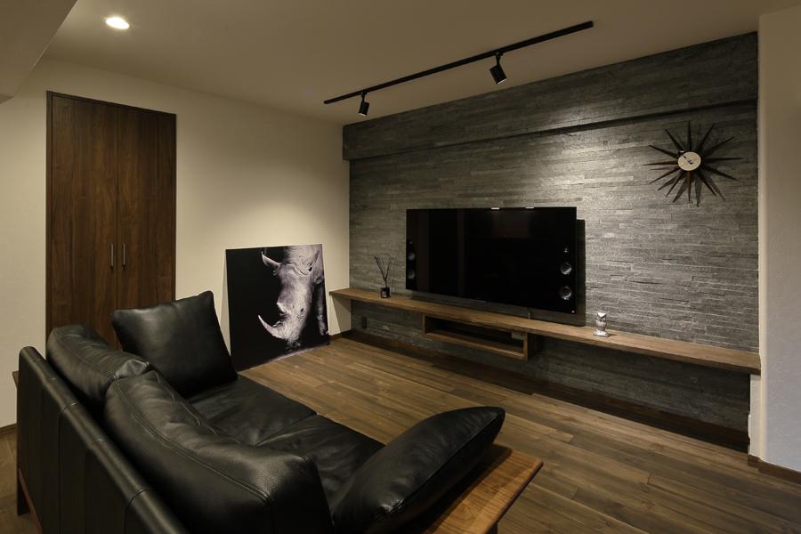 自然石に似たスタイリッシュな壁面が印象的なリビングです。壁いっぱいに枕棚を造作してテレビボードに使用。棚下に空間があるので大型家電があっても狭く感じません。裸足も心地よい無垢パイン材を床に敷きました。