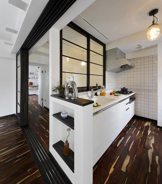 透明なガラス仕様の間仕切りで隣室と区切ったスタイリッシュなキッチンです。壁に囲まれて狭く孤立した個室が一変！LDや奥の部屋を眺めながら家事が進みます。奥の壁はタイルを使い颯爽としたグラフチェック柄に。