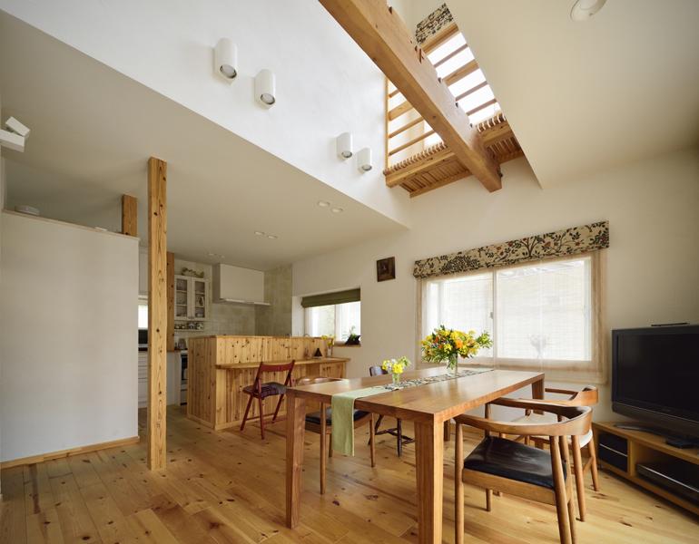 吹き抜けから光こぼれる開放的なLDKです。無垢材や珪藻土などの自然素材を使った壁・天井にヌケを造り空気が回流する空間プラン。あらわになった「柱・梁」にはクリアな塗装をかけて美しい木目を惹きたてました。キッチンカウンターはゲストと会話のはずむオープンスペースに。リビングの開放感は折り紙付き！