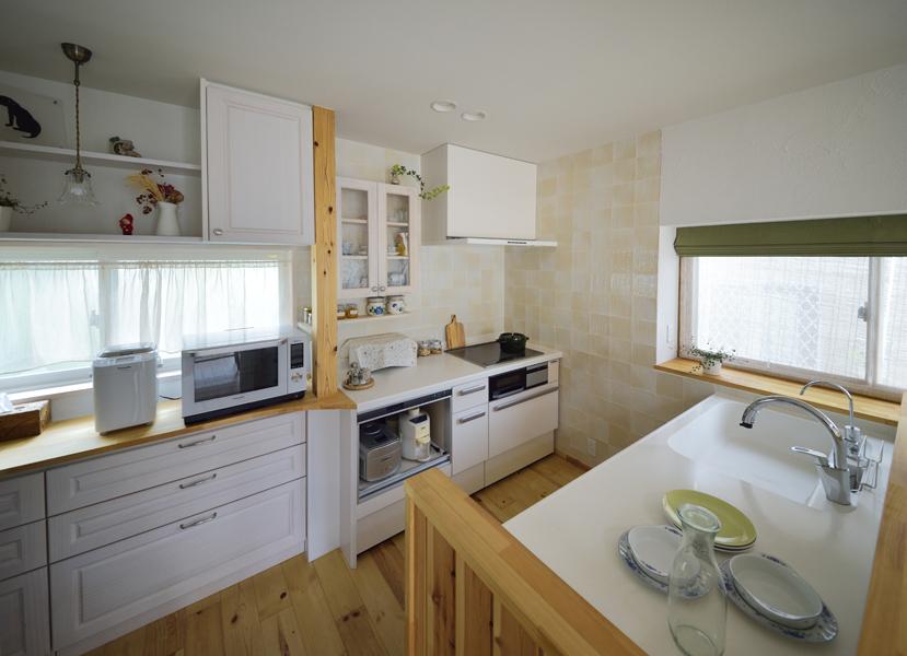 白を基調に木素材を合わせたナチュラルで優しい雰囲気のキッチンです。シンクからは対面するリビングを広々と見通せ 会話も弾みそう。中は2人で調理してもぶつからない余裕のサイズ。窓に沿った大容量の収納には二世帯分の食器類がすっきり収まりました。