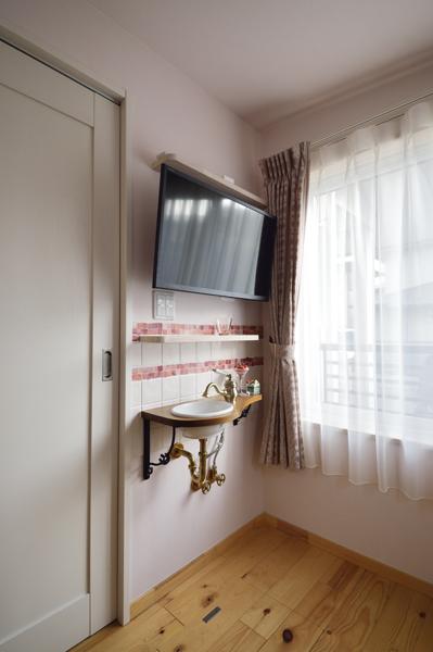 増築したお母様の洋室に設えた手洗いスペースです。華やかな印象のタイルを正面に施工して水はねに対応。増設配管や棚受けパーツにもデザイン性を追求し 全体がお洒落なオブジェのよう。H邸は独立した水回りが特徴で このほかにも汚れ物専用のスロップシンクや洗面コーナーを邸内に造作しています。