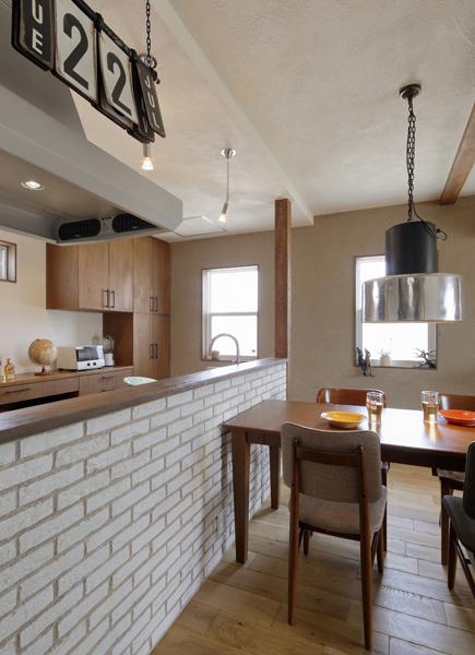 ペンダントライトが印象的なダイニングです。インダストリアル調のカレンダーが個性的。カウンターは表情豊かなブリックタイルと色むらを出した木素材で爽やかな風合い。