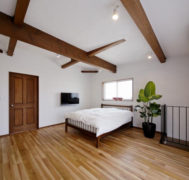 木の梁を眺めるナチュラルな洋室です。壁かけのテレビが「絵画」のような立ち位置で白い室内にアクセントと彩りを加えました。濃淡が際立つ床フローリングも魅力的。