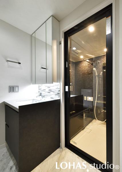 ホテルライクな空間に仕上げた洗面室とユニットバスです。より広さを感じていただけるよう、ドアは透明なものをセレクトしました。洗面化粧台は既存のものをカラーチェンジすることで馴染ませています。