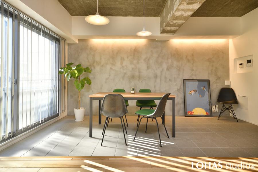 リビングと同じように色彩を抑えてデザインしたダイニングです。躯体現しの壁にモルタルを施工し、自然と出来たムラのあるラフ感が、家具やグリーンがより鮮やかに映える空間になりました。もともとあった床の段差を活かして土間のように仕上げたため、リビングの床をベンチのように使うこともできます。