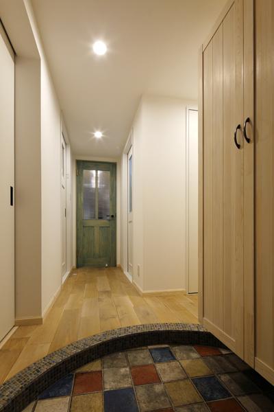 アーチ状の上り框を造作したナチュラルな装いの玄関です。フレンチシックな大き目のタイルが印象的。天井近くまでたっぷり使える収納棚をご用意しました。肌の白いホワイトオークを乱尺で床に施工しデザイン性を持たせました