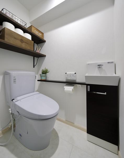 ストイックな印象を受けるシンプルなトイレです。デッドスペースを活かして棚を造作。天井にはナチュラルな質感のエコクロスを採用。床は洗面所水に強いフロアタイルです。