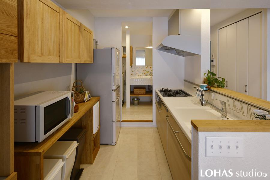 自然石のように表情豊かなフロアタイルを施工したキッチンです。片側は洗面室へ、もう片方はリビングに抜けるオープンな間取り。正面にはリビングが広がります。