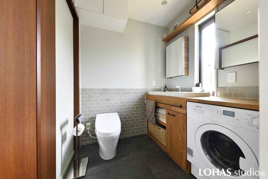 納戸を広く取る都合上、コンパクトにまとめた水回りです。洗濯が好きだという奥さまのために、シンクは大きなものをチョイス。グレートーン＋木目のナチュラルテイストで清潔感たっぷりです。