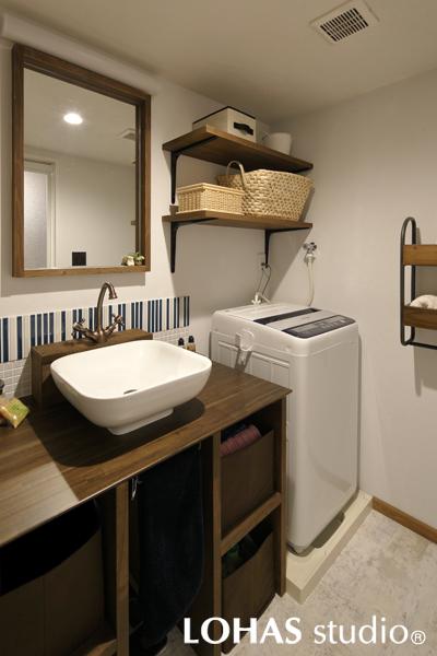 ストライプのタイルパターンを装飾したお洒落な洗面室です。深い色合いの造作洗面台にはぽったりとしたフォルムの洗面ボウルをご採用。水栓はアンティーク調のツル首水栓です。壁にはシンプルな棚を造作しました。