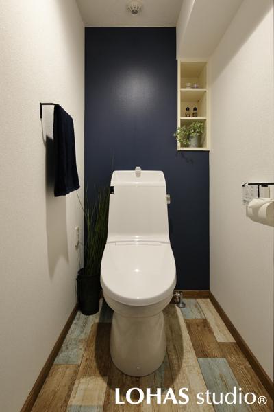 カフェのようなテイストの大人可愛いトイレです。擦れ感のある乱尺の床デザインがお洒落。奥の壁を大胆な濃色で塗装しました。下がり壁に合わせてディスプレイにもなる収納を追加しています。