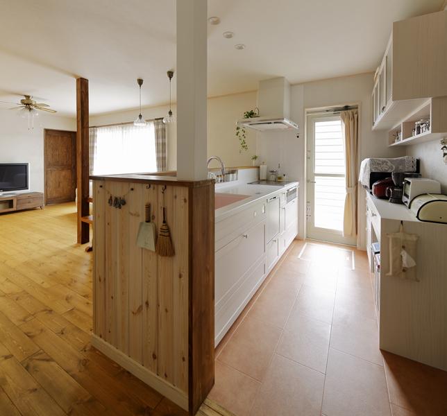 リビングを眺めるオープンタイプのキッチンです。2室+縁側をひとつにまとめ壁を無くし大空間を造りました。シンクをL字に囲んだ腰壁が淡いピンクのキッチンと好相性。シンク前にはニッチを造り小瓶や小物が置けるように。棚やパントリーを新設して収納力も上がりました。