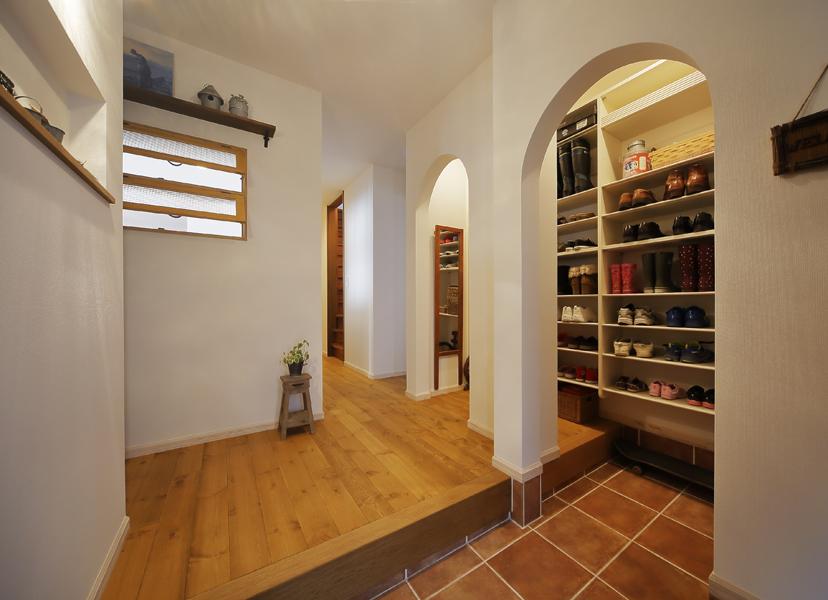 アーチの下がり壁が印象的な玄関です。リビングにも同じデザインを入れて世界観を1つに。土間まで張り出すシューズインクロークは隣接のDKを一部活用。5人家族の靴・傘がたっぷり入ります。壁は板張りから白クロスに変更しLDK側に内窓を造りました。玄関とリビングがゆるくつながります。