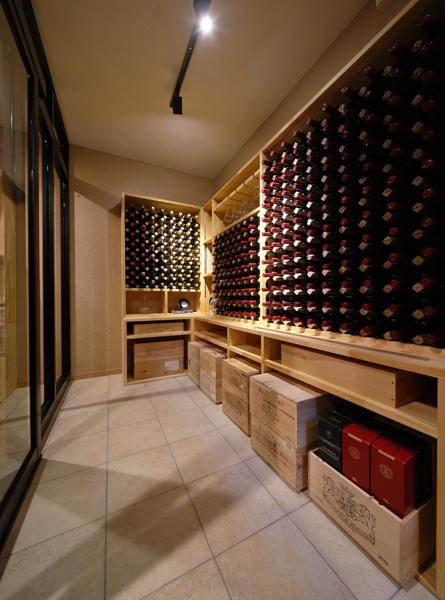ワインの木箱やボトル・グラスがスッキリと収まったワイン貯蔵室です。透明感のあるガラスサッシで開口部を塞ぎ個室を造りました。床にはグレーのタイルを施工しています。