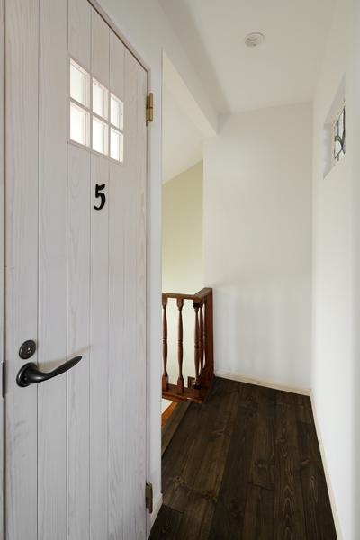 2階LDKに繋がる階段ホールです。木目の透け感が堪らないアンティーク調の扉はトイレの出入り口。フレンチシックなミルク色を黒パーツが引締めました。ヴィンテージ調の床にもとてもよく馴染んでいます。壁にはステンドグラスが入りホールに美しい色彩が加わりました。