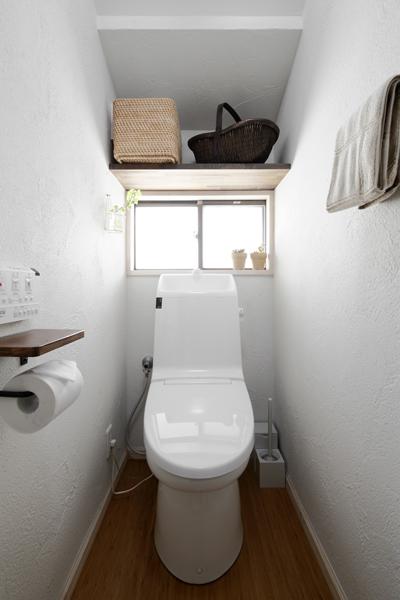 清潔感あふれる白トーンのトイレです。凸凹が少なくお手入れカンタンな すっきりフォルムの便座に新品交換しました。窓上に便利な棚を造作して収納力もアップです。