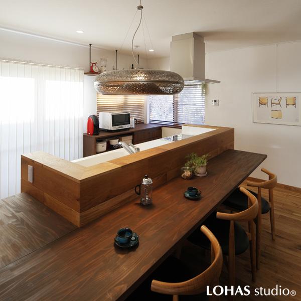 無垢パイン材で造作したダイニングカウンター。北欧のデザイナーズ照明・チェアで洗練された景観に。目の前はバルコニーで眺めも良好。
