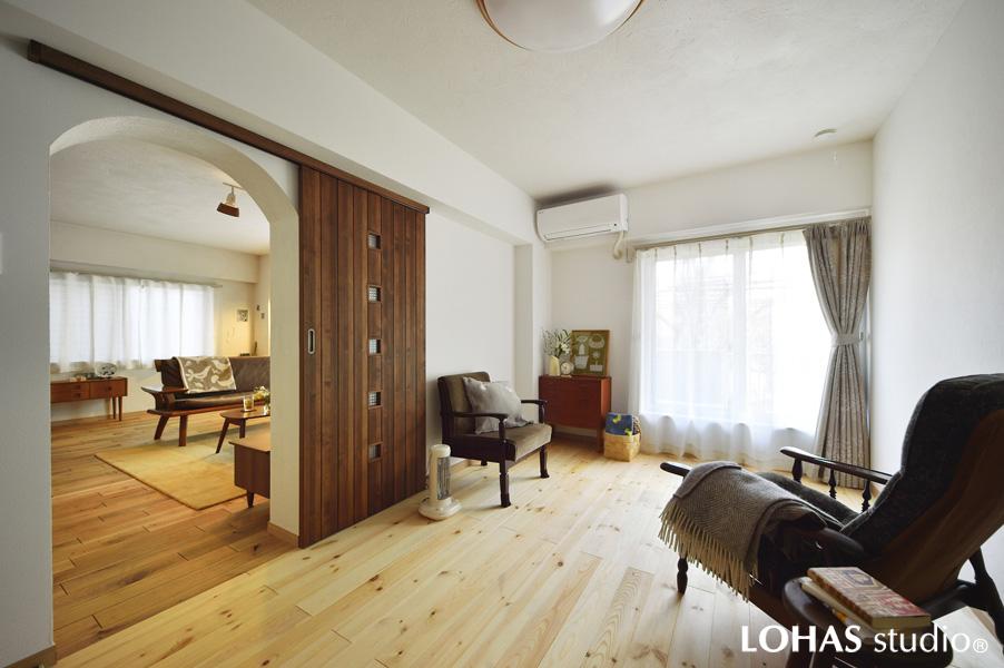 アーチ状の開口でLDKとつながる寝室です。LDK間の壁を厚くしてTV配線を内部にきれいに収めるように工夫。引き戸を閉じれば閑静な個室に早変わりです。床は明るいトーンの無垢パイン材でLDKと趣きを一新。既存の和室・押入れを取り込んだことで悠々とした広さが生まれています。