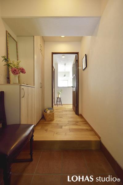 幅広の通路を活かして天井サイズの大型収納を設置した優美な玄関です。アンティーク家具とも馴染みのよいテラコッタ調タイルを土間に、室内扉は無垢材を使って上質な装いに仕上げました。セミオープンに造作したキッチンの先から自然の光と風が爽やかに届きます。