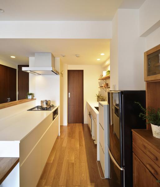 2列タイプの白いキッチンです。レンジフードは煙の捕集力が高いブーツ型。水栓はカーブの可愛いツル首をご採用。艶のある素材に木の風合いを合わせました。