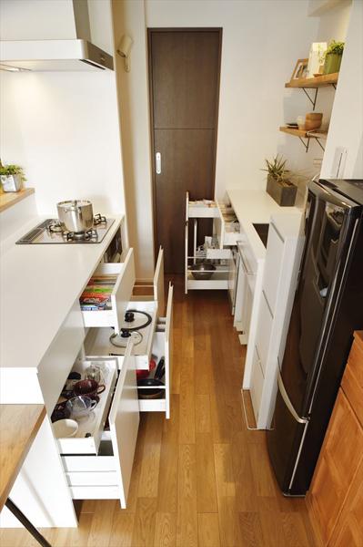 面を揃えて並べたスッキリした印象のキッチン収納です。左奥にレンジが置けるパントリーをご用意。壁の棚は「飾る楽しみができた」と仰るお気に入りポイント。