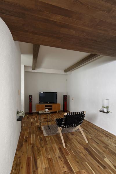 杉の梁が空間を引き締めるリビング兼シアタールームです。箱型空間で音響効果は良好! 入り口の天井部は少し低く造作して個室感を造りました。左手オープン開口から寝室に繋がります。